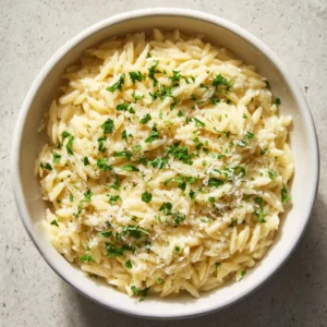 Close-up of Creamy Garlic Parmesan Orzo in a white bowl showing the glossy ivory cream sauce and fluffy cheese.
