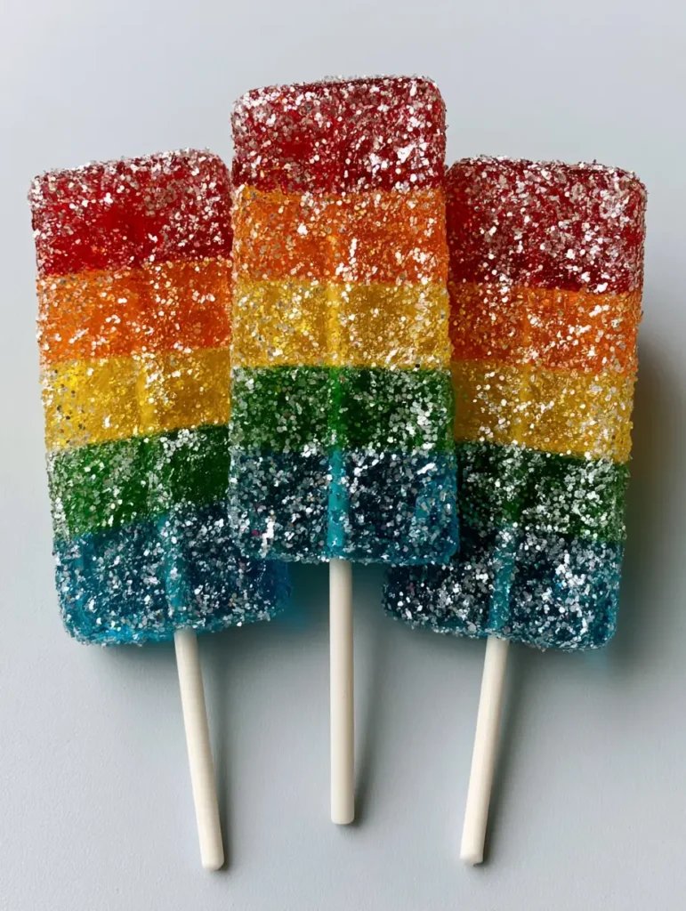 A close-up of three Tequila Gummy Wands showing the translucent horizontal gelatin layers and sparkling silver glitter. (Tequila Gummy Wands)