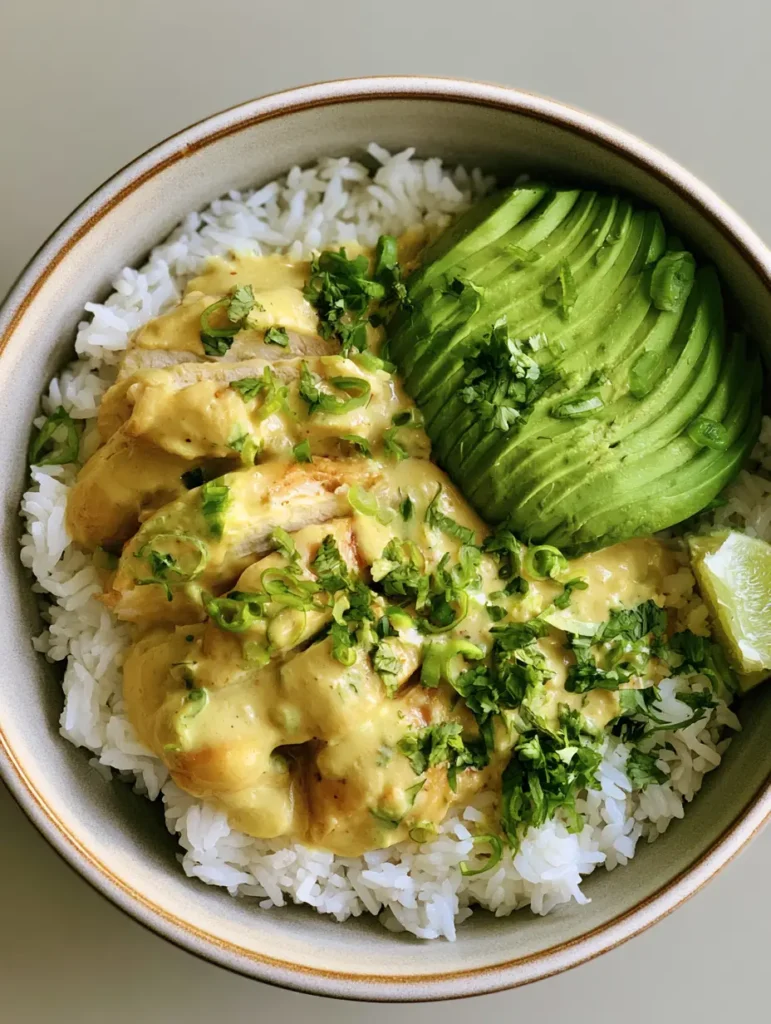 Coconut Chicken Rice Bowl with Creamy Lime and Avocado 1 Handheld photo of a Coconut Chicken Rice Bowl with fresh garnishes and sliced green scallions.