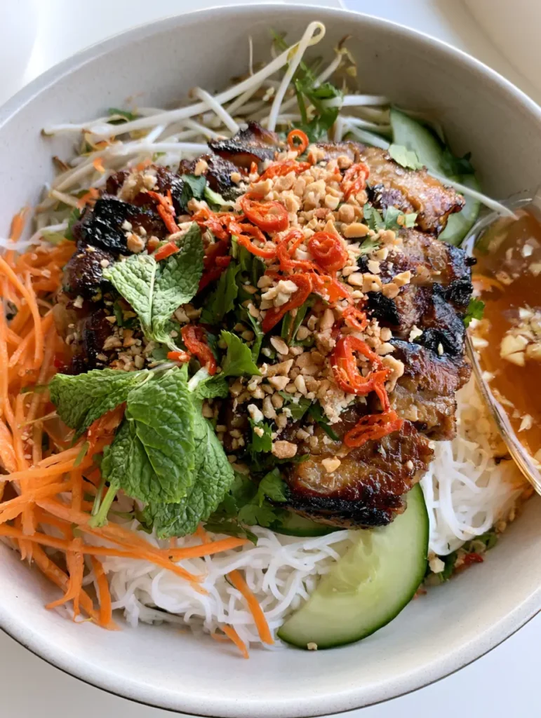 A top-down view of a Vietnamese Noodle Salad bowl with a side of amber fish sauce dressing.