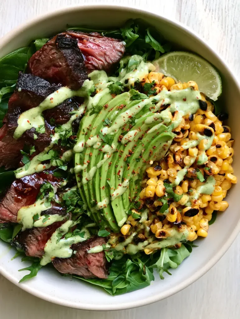 Steak and Avocado Bowl with Creamy Cilantro Lime Sauce 2 Top-down view of a Steak and Avocado Bowl with medium-rare steak, bright green avocado, and charred corn kernels.