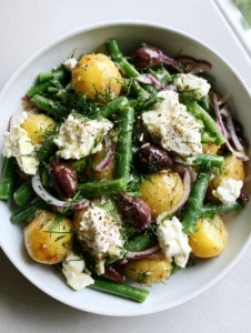Close-up handheld smartphone photo of Mediterranean Greek Potato Salad featuring boiled yellow potatoes, blanched green beans, and rustic feta crumbles.