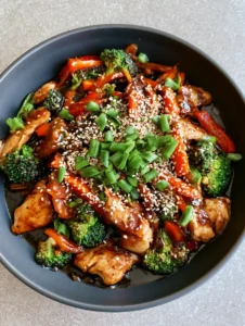 Overhead shot of seared chicken breast pieces and charred broccoli in a dark savory stir fry sauce.