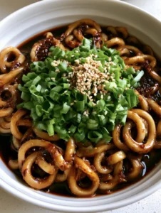 A handheld smartphone photo of glossy dark soy sauce glaze over thick udon noodles. (Easy Udon Noodle Sauce)