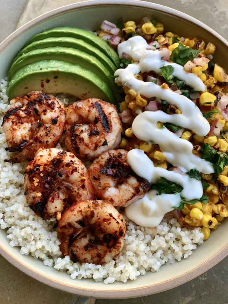 Overhead view of a Grilled Shrimp Bowl showing the charred yellow corn salsa and sliced avocado on white quinoa.