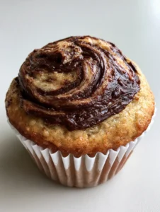A handheld smartphone photo showing the dense light-tan crumb of Nutella Banana Swirl Muffins.