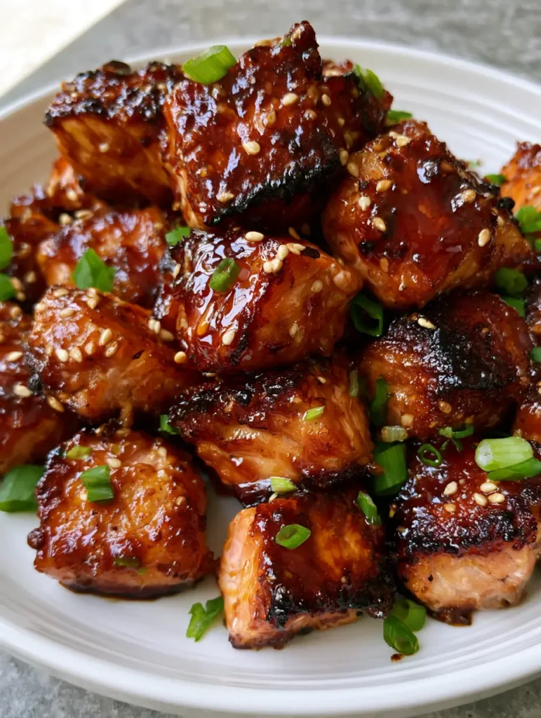 Honey Garlic Salmon Bites: The Crispy, Sticky 15-Minute Dinner 1 Bite-sized honey garlic salmon pieces topped with toasted white sesame seeds and chopped green scallions.