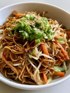 Close up of stir-fried wheat noodles with a dark savory soy glaze and green scallions. (Easy Chow Mein Recipe)