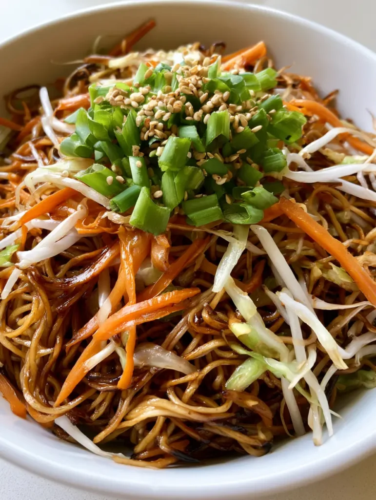 Easy Chow Mein Recipe: Better Than Takeout in 20 Minutes 1 Overhead view of Easy Chow Mein Recipe with julienned carrots, cabbage, and fresh bean sprouts in a white bowl.