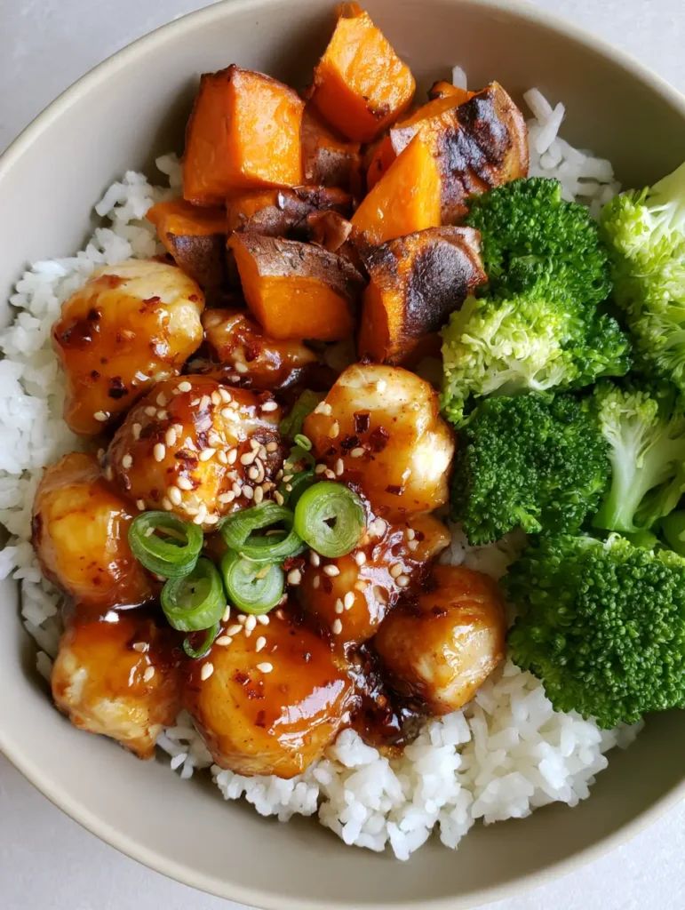 Hot Honey Chicken Bowls with Roasted Sweet Potatoes and Broccoli 2 Close up of sticky hot honey chicken with red chili flakes and sesame seeds. (Hot Honey Chicken Bowls)