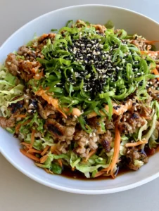 Overhead smartphone photo of Egg Roll in a Bowl in a white ceramic bowl showing glossy sauce and sesame seeds.