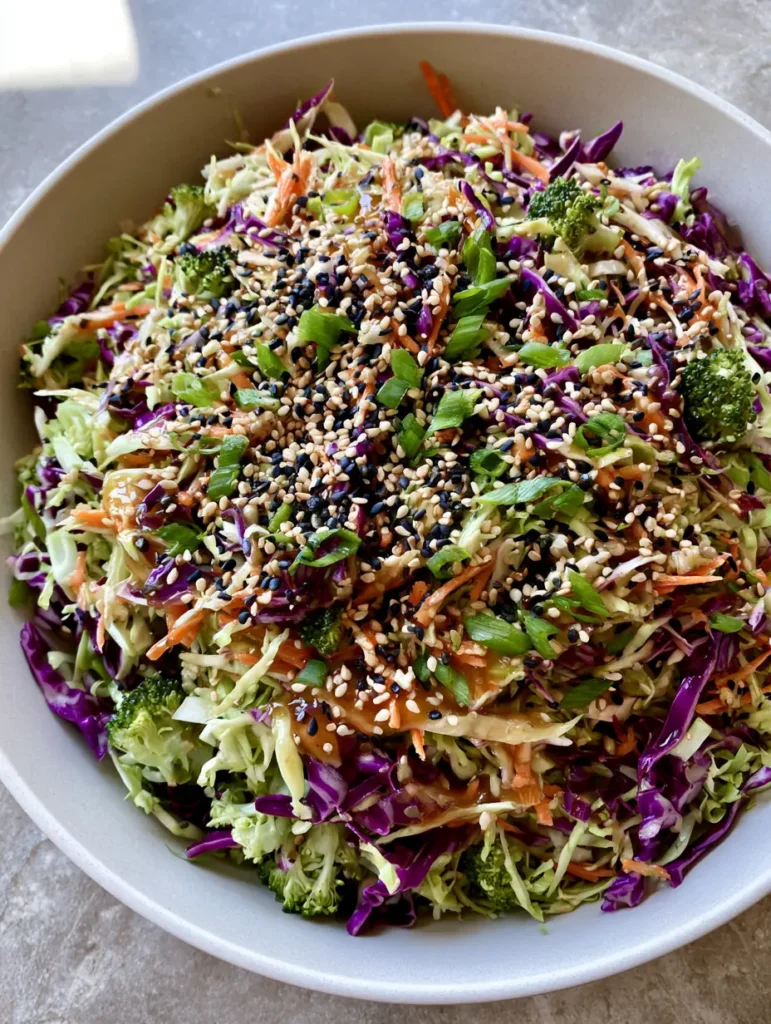 Close-up of the textures in the Asian Cabbage Salad, highlighting the tiny raw broccoli florets and black sesame seed garnish.