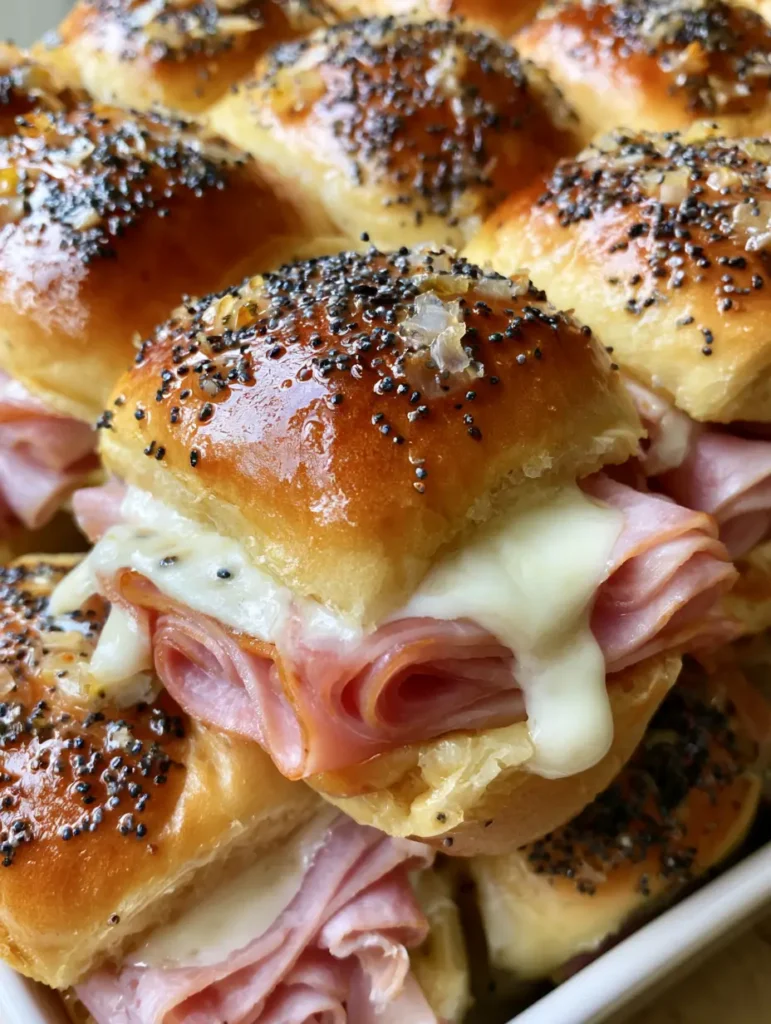 Close-up of melted Swiss cheese drooping over the sides of Hawaiian Ham and Cheese Sliders.