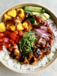 Close-up handheld photo of a Hawaiian Chicken Bowl with glossy teriyaki chicken and caramelized pineapple on a bed of jasmine rice.