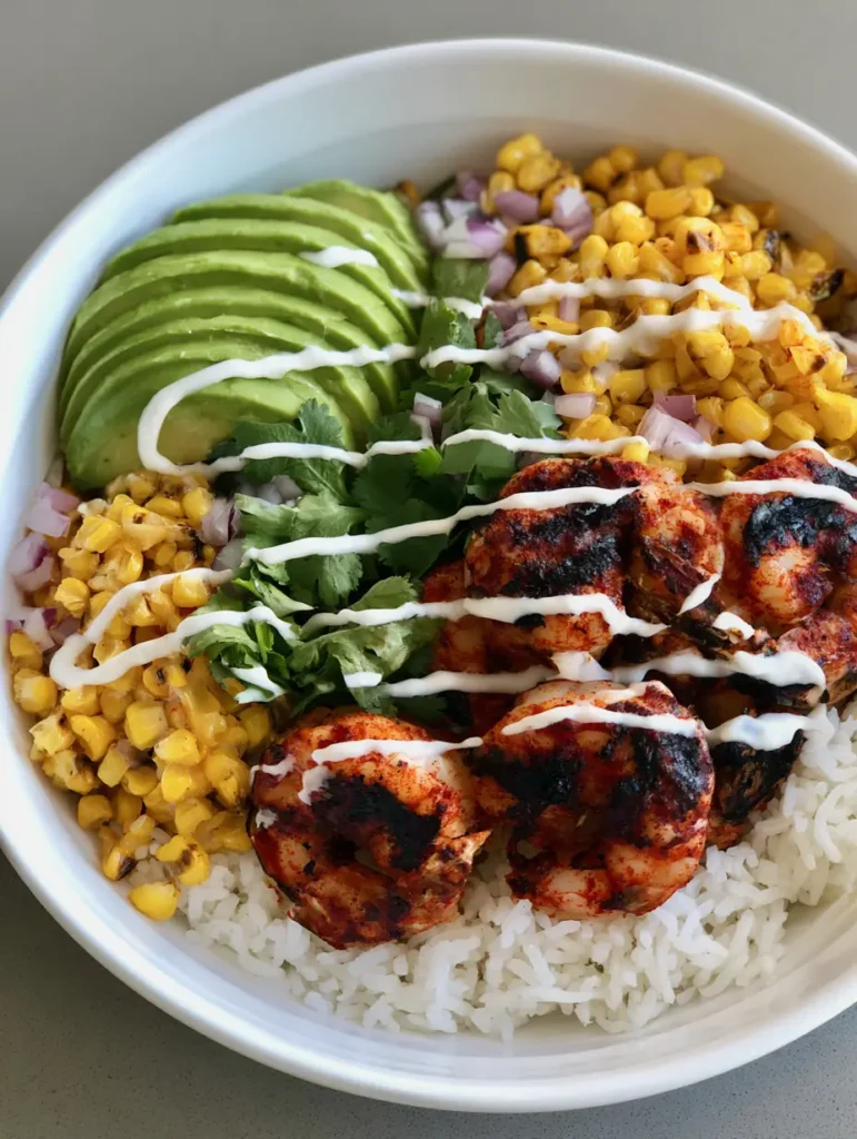 Handheld photo of a Grilled Shrimp Bowl showing the red spice rub on the shrimp and the vibrant green cilantro sprigs.