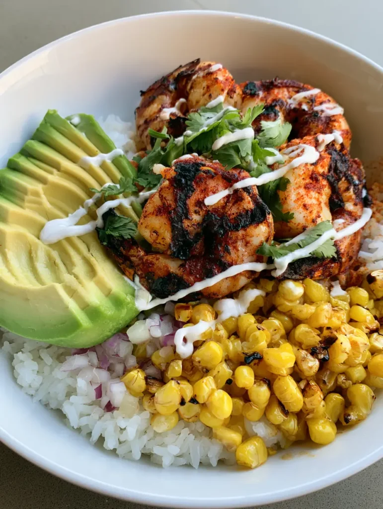 A wide angle shot of the Grilled Shrimp Bowl highlighting the fluffy white rice base and the creamy lime sauce drizzle.