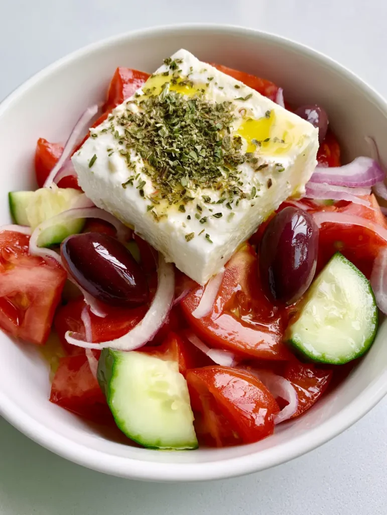 Authentic Greek Salad: The Ultimate Traditional Horiatiki Recipe 1 A thick rectangular block of feta cheese topped with dried oregano and olive oil drizzle on an Authentic Greek Salad.