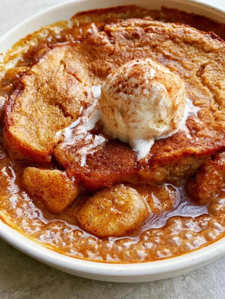 Rustic white ceramic dish filled with Southern Banana Cobbler, featuring caramelized bananas and a golden-brown cake crust.