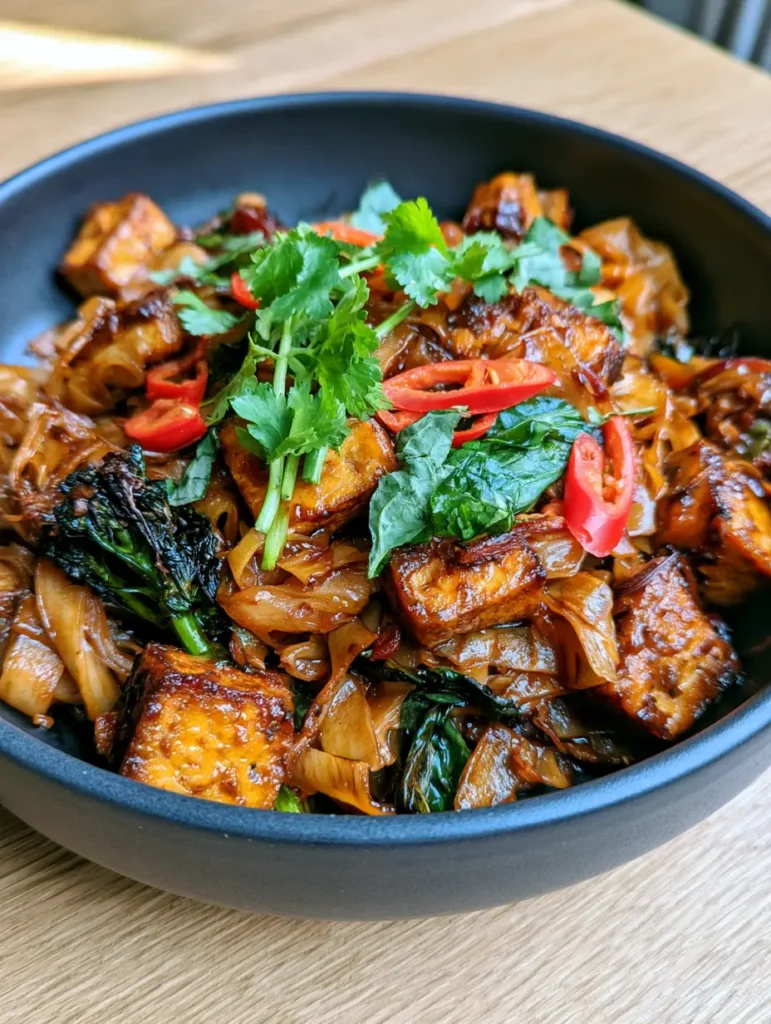 Thai Drunken Noodles (Pad Kee Mao) with Tofu and Basil 1 Close-up of charred Chinese broccoli and bright red chilies in a plate of Thai Drunken Noodles.