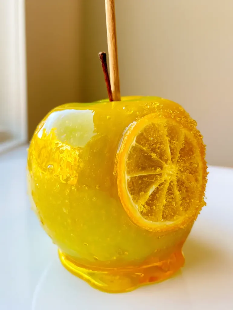 Detailed view of the yellow candy glaze and dehydrated lemon slice on Pineapple Lemonade Candy Apples.